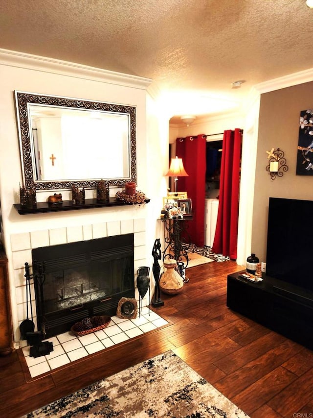 living area featuring ornamental molding, a fireplace, a textured ceiling, and wood finished floors