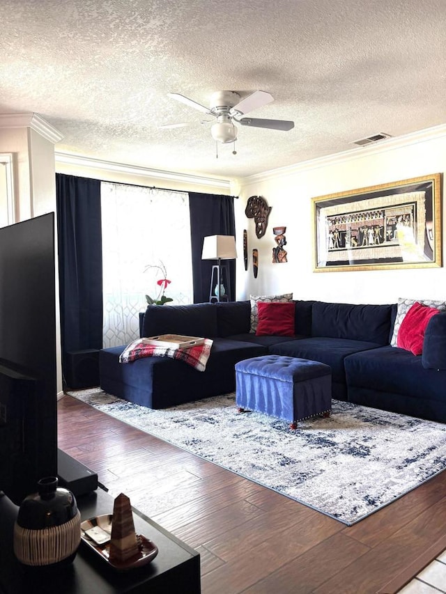 living room featuring a ceiling fan, visible vents, ornamental molding, and wood finished floors