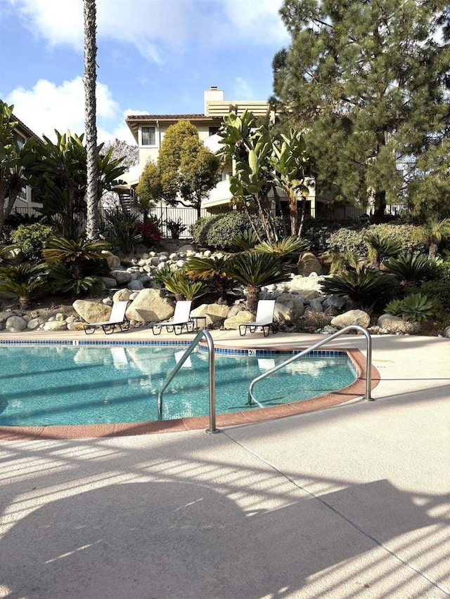 pool featuring fence and a patio