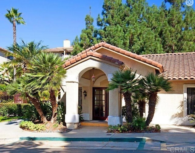 view of front of house with a chimney, a tile roof, and stucco siding