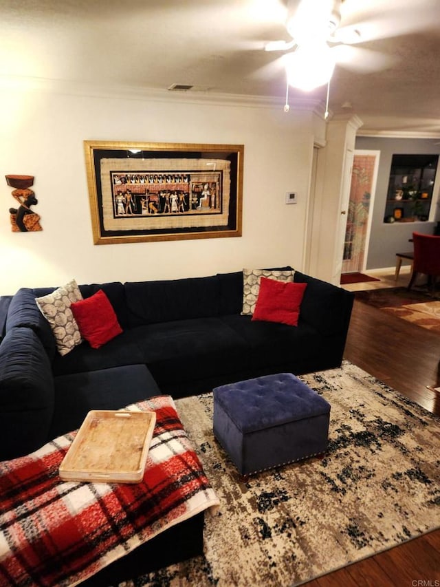 living area featuring a ceiling fan, visible vents, crown molding, and wood finished floors