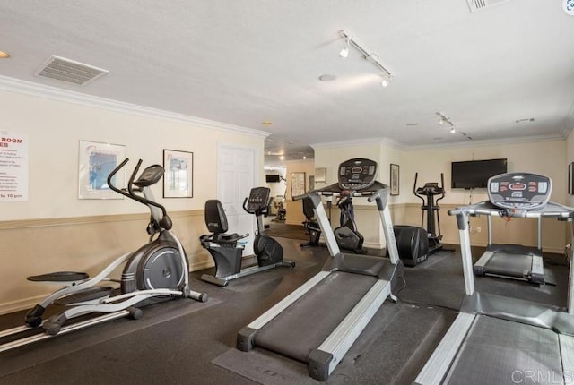 gym with track lighting, visible vents, and crown molding