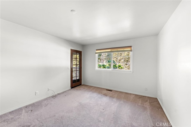 unfurnished room featuring light colored carpet, visible vents, and baseboards