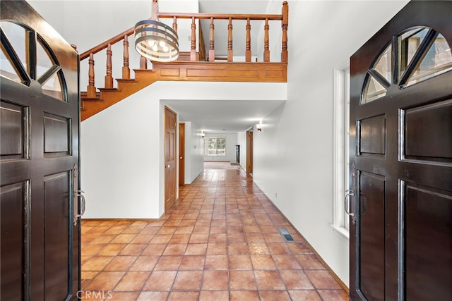 entryway featuring light tile patterned floors, a high ceiling, and visible vents