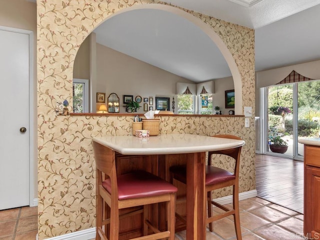 kitchen with light tile patterned flooring, lofted ceiling, and kitchen peninsula