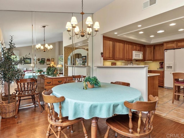 dining room with a raised ceiling, a notable chandelier, and light wood-type flooring