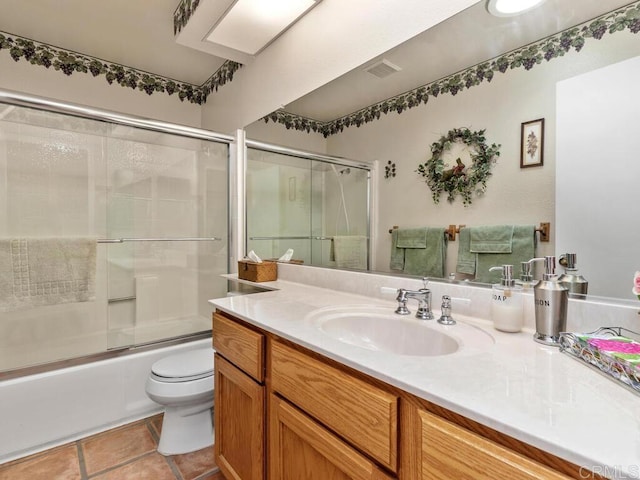 full bathroom featuring shower / bath combination with glass door, vanity, toilet, and tile patterned flooring