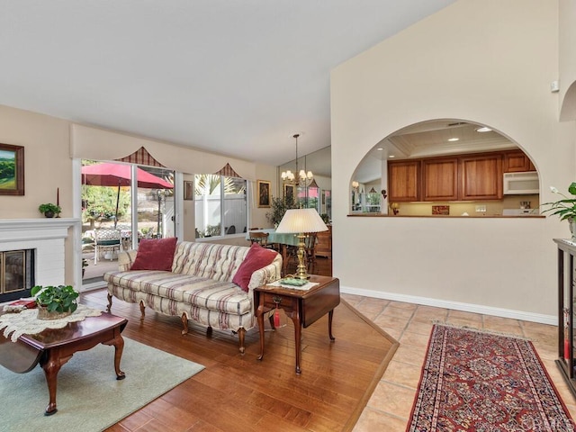 living room featuring vaulted ceiling, a brick fireplace, light tile patterned flooring, and an inviting chandelier