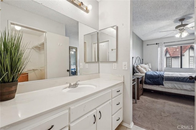 bathroom with ceiling fan, vanity, and a textured ceiling