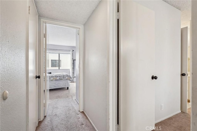 hall featuring light colored carpet and a textured ceiling