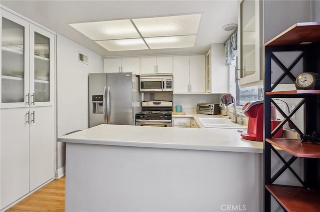 kitchen with sink, kitchen peninsula, white cabinets, and appliances with stainless steel finishes