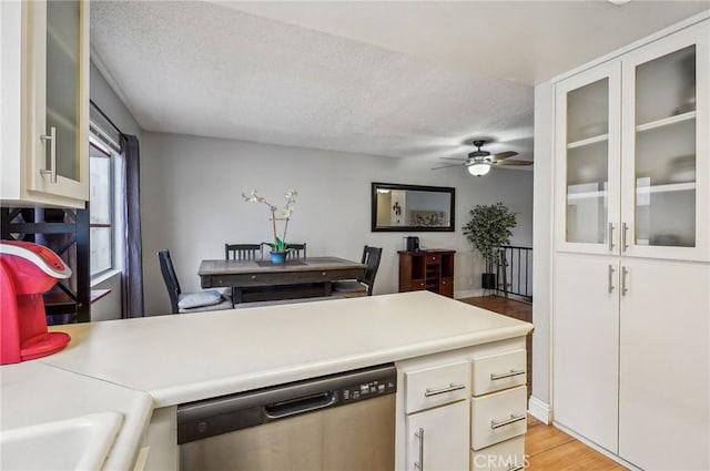 kitchen with white cabinetry, stainless steel dishwasher, light hardwood / wood-style floors, and a textured ceiling