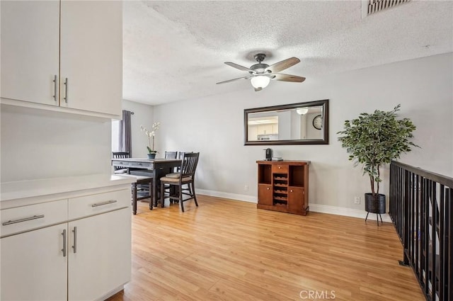 dining room with ceiling fan, a textured ceiling, and light hardwood / wood-style floors