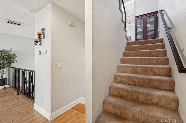 stairway featuring wood-type flooring and a textured ceiling