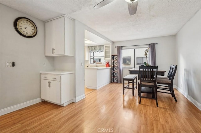 dining room with ceiling fan, a textured ceiling, and light wood-type flooring