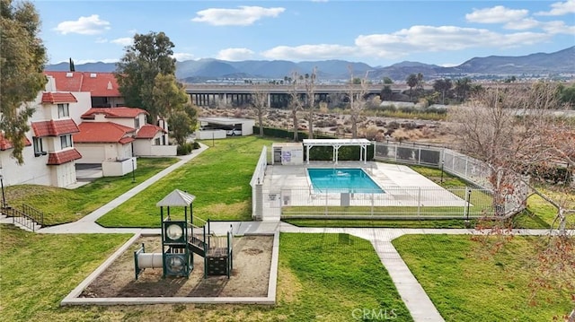 view of swimming pool featuring a mountain view, a lawn, and a playground