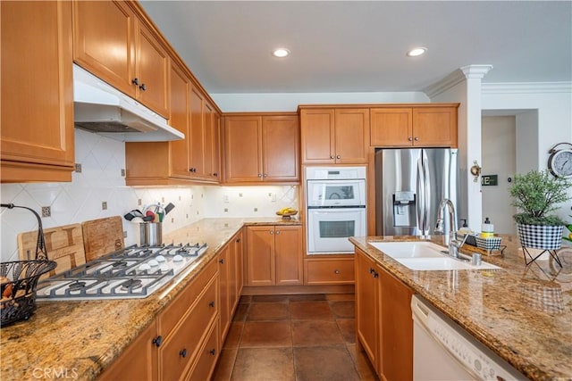 kitchen with appliances with stainless steel finishes, tasteful backsplash, sink, crown molding, and light stone countertops