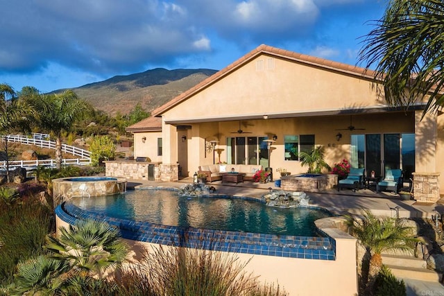 view of swimming pool with an in ground hot tub, ceiling fan, exterior kitchen, and a mountain view