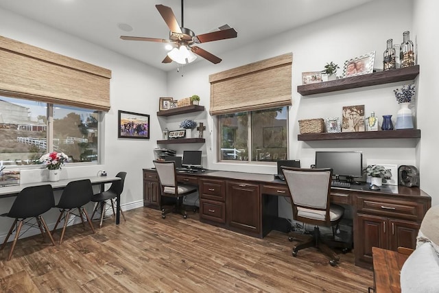 office with dark wood-type flooring, built in desk, and ceiling fan