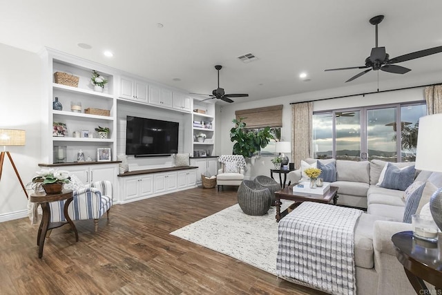 living room with dark wood-type flooring, ceiling fan, and built in shelves