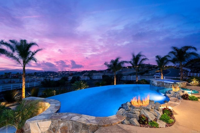 pool at dusk featuring an in ground hot tub