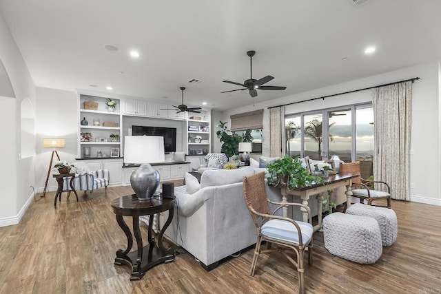 living room with hardwood / wood-style flooring, ceiling fan, and built in shelves