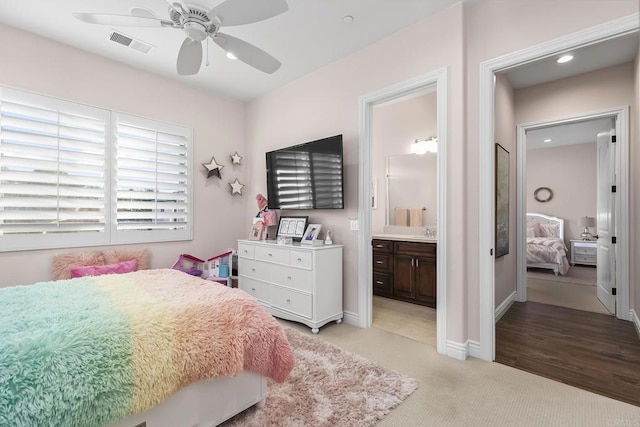 bedroom with ensuite bath, light colored carpet, and ceiling fan