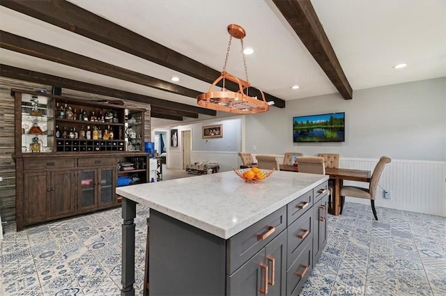 kitchen featuring a kitchen island, pendant lighting, beamed ceiling, a breakfast bar area, and gray cabinetry