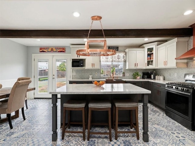 kitchen featuring sink, white cabinets, hanging light fixtures, a center island, and stainless steel gas range oven