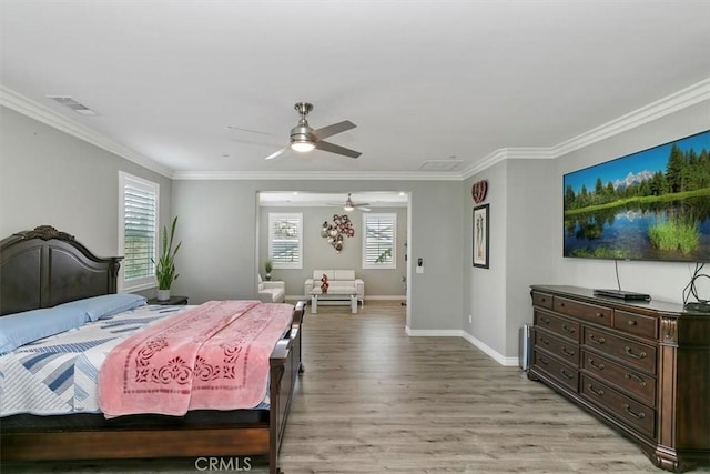 bedroom featuring multiple windows, crown molding, and light hardwood / wood-style flooring