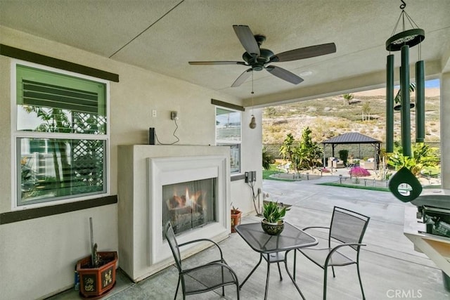 view of patio / terrace with a gazebo, ceiling fan, and exterior fireplace