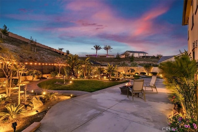 patio terrace at dusk featuring a yard