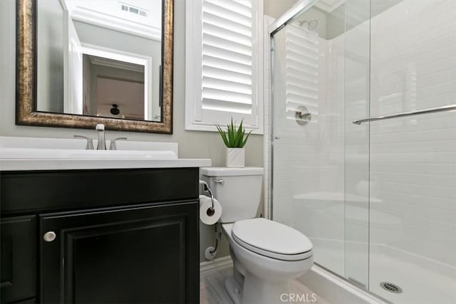 bathroom featuring vanity, a shower with shower door, and toilet