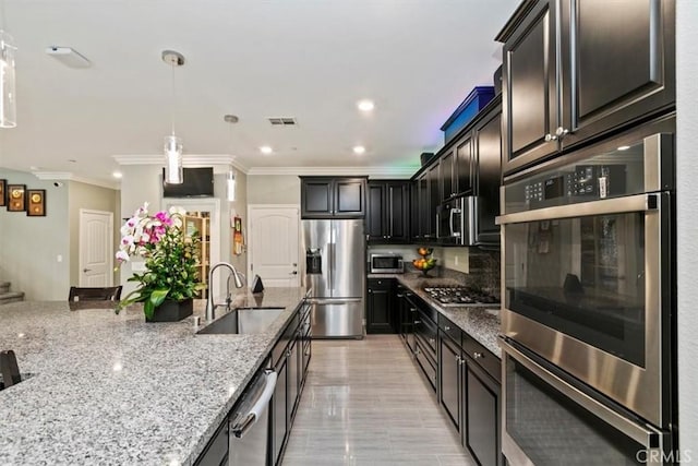 kitchen with sink, ornamental molding, appliances with stainless steel finishes, light stone countertops, and decorative backsplash