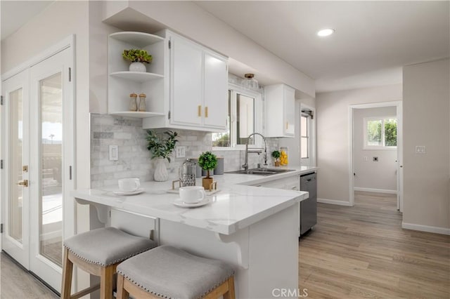 kitchen featuring sink, decorative backsplash, a breakfast bar, and white cabinets