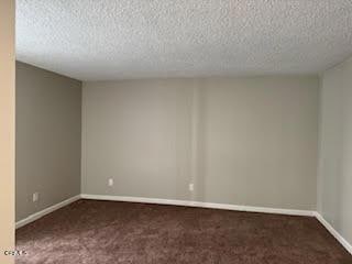 carpeted empty room featuring a textured ceiling