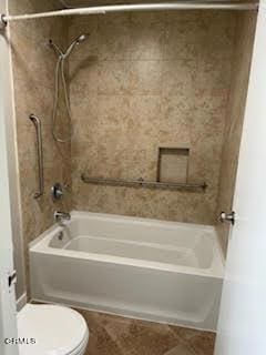 bathroom featuring tiled shower / bath and toilet