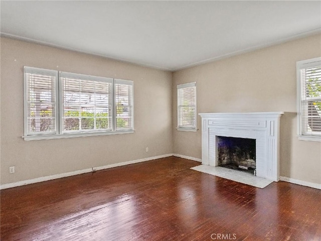 unfurnished living room featuring a brick fireplace and dark hardwood / wood-style floors