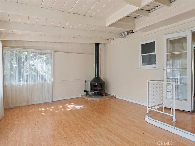 unfurnished living room featuring beam ceiling, wood-type flooring, wooden ceiling, and a wood stove