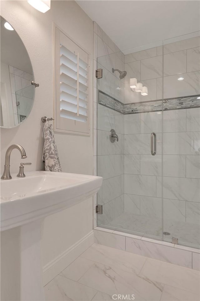 bathroom with a stall shower, marble finish floor, and baseboards