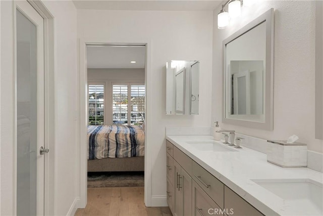 bathroom featuring double vanity, a sink, wood finished floors, and ensuite bathroom