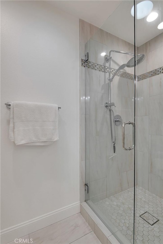 bathroom with a stall shower and baseboards