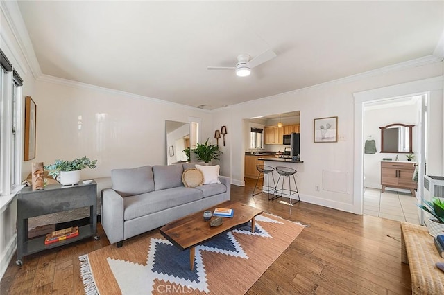 living room with crown molding, ceiling fan, and light hardwood / wood-style floors