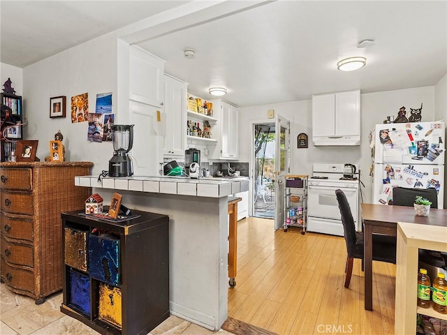 kitchen with white appliances, light hardwood / wood-style flooring, white cabinetry, tile countertops, and kitchen peninsula