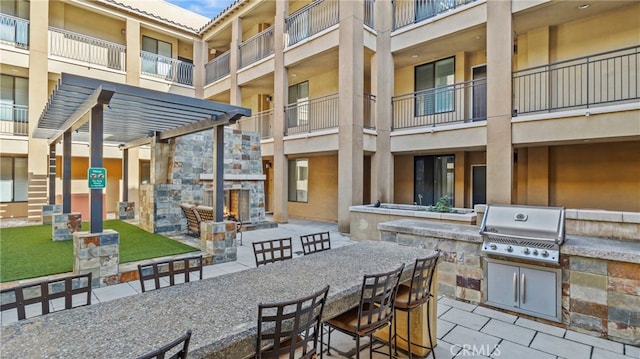 view of patio / terrace with area for grilling, a grill, an outdoor stone fireplace, a pergola, and exterior bar