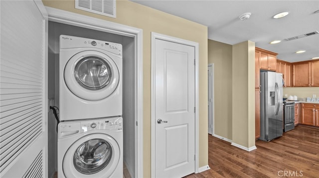 clothes washing area with dark wood-type flooring and stacked washer and dryer