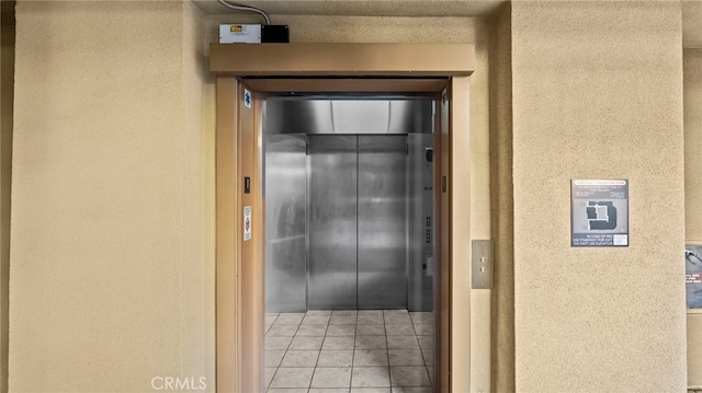 corridor featuring elevator and light tile patterned flooring