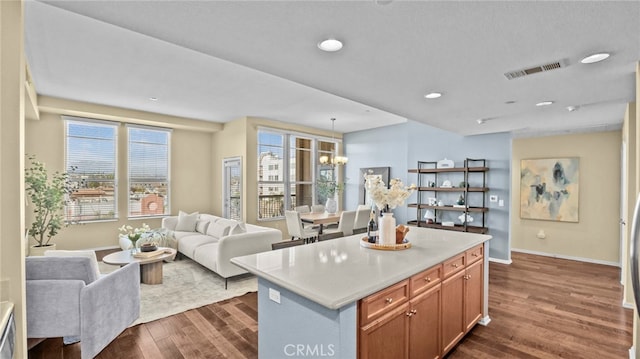 kitchen with dark wood-type flooring, a center island, an inviting chandelier, and decorative light fixtures