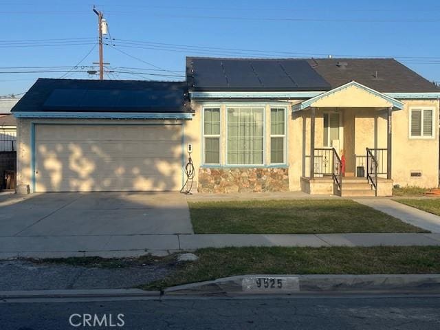 view of front of property with a garage, a front yard, and solar panels