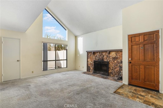 unfurnished living room featuring a stone fireplace, high vaulted ceiling, and carpet